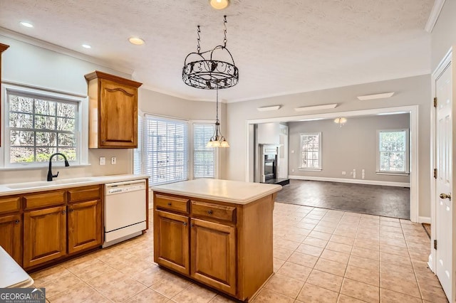 kitchen with a glass covered fireplace, brown cabinets, white dishwasher, and a sink