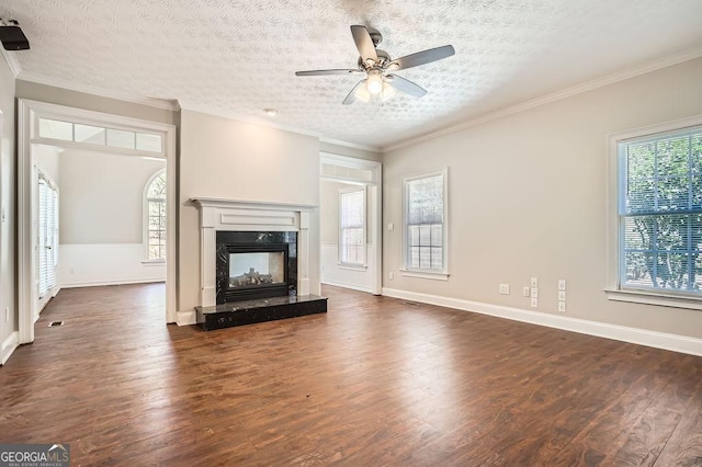 unfurnished living room featuring a textured ceiling, crown molding, a fireplace, and dark wood-type flooring