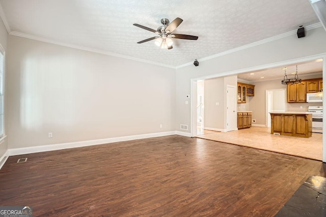 unfurnished living room featuring baseboards, wood finished floors, and crown molding