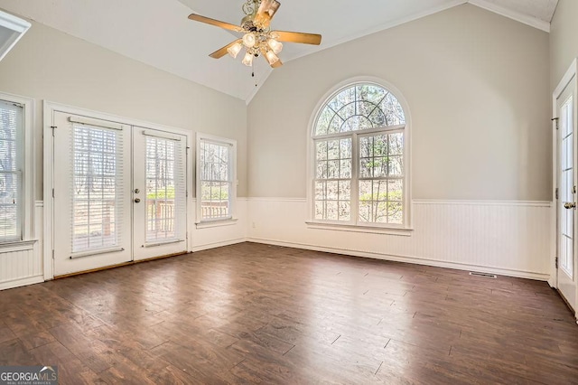 empty room featuring lofted ceiling, french doors, wainscoting, and wood finished floors