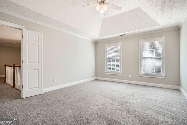 empty room featuring carpet, a raised ceiling, visible vents, and crown molding