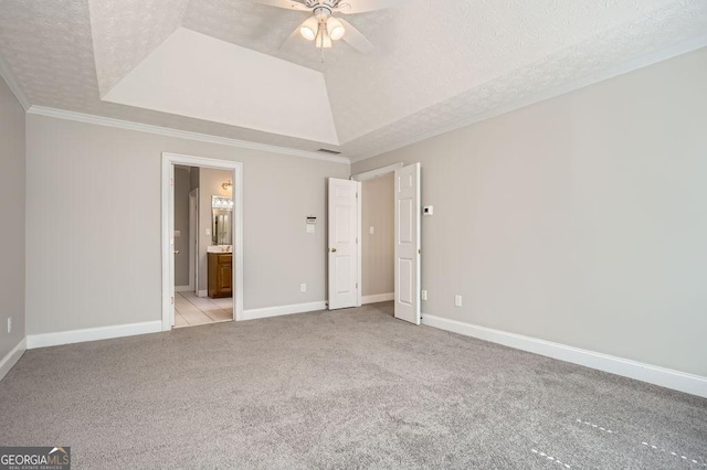 unfurnished bedroom with baseboards, a raised ceiling, light colored carpet, ornamental molding, and a textured ceiling