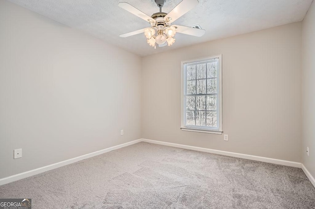 carpeted spare room featuring a textured ceiling, baseboards, and a ceiling fan