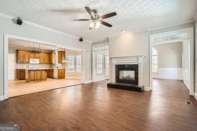 unfurnished living room featuring a textured ceiling, a fireplace, wood finished floors, visible vents, and crown molding