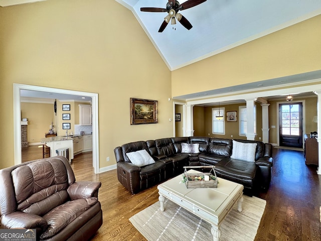 living area featuring high vaulted ceiling, wood finished floors, decorative columns, and baseboards