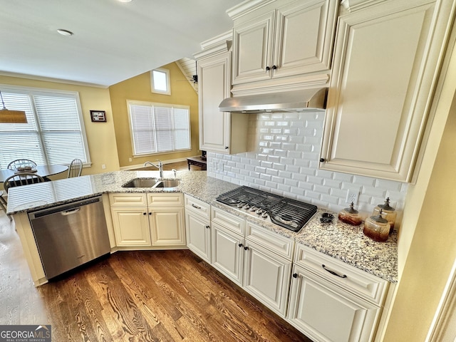 kitchen featuring dark wood finished floors, appliances with stainless steel finishes, a peninsula, wall chimney range hood, and a sink