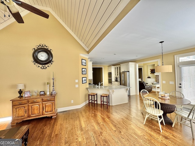 dining room with a ceiling fan, crown molding, baseboards, and wood finished floors