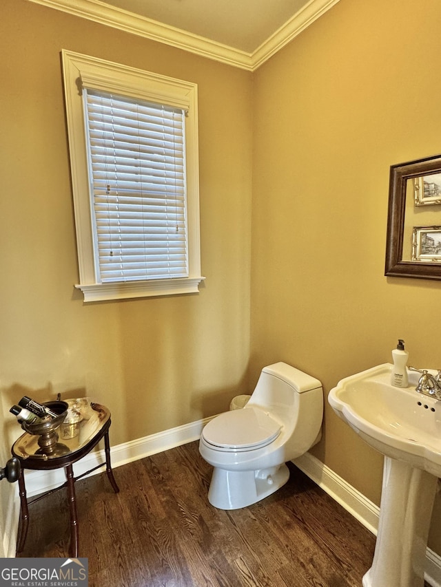 half bath featuring ornamental molding, wood finished floors, toilet, and baseboards