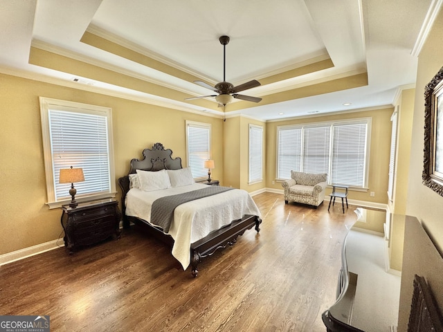 bedroom featuring ornamental molding, a raised ceiling, baseboards, and wood finished floors