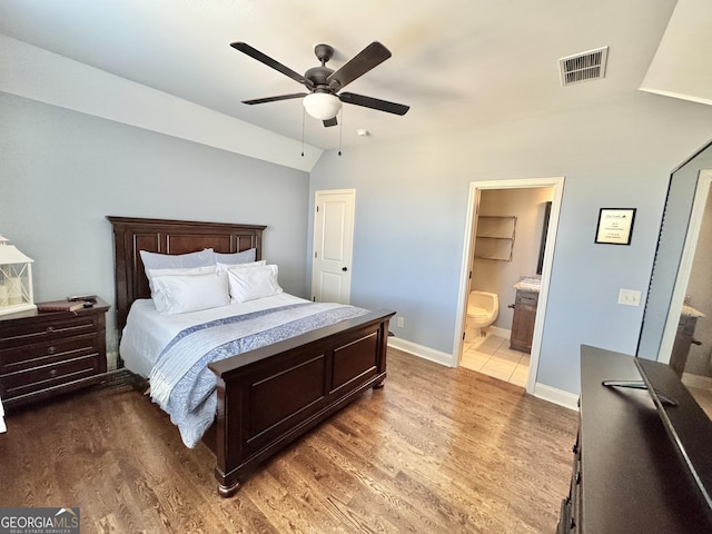 bedroom with baseboards, visible vents, vaulted ceiling, and wood finished floors