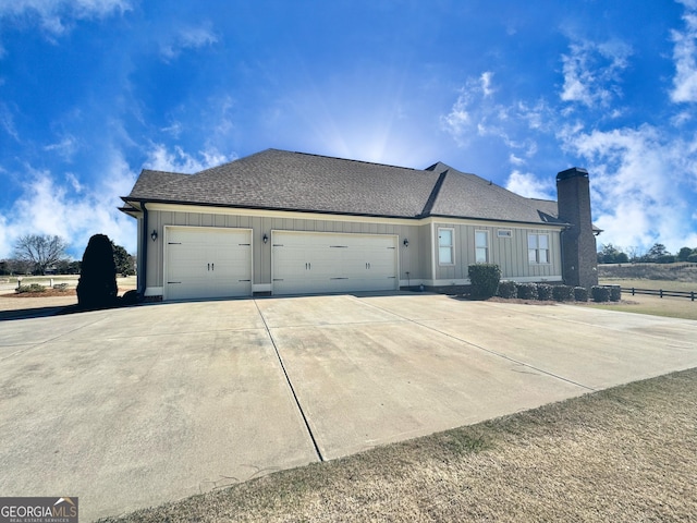 view of property exterior with a garage, roof with shingles, driveway, and a chimney