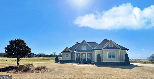 view of front of house with a chimney, a front lawn, and board and batten siding