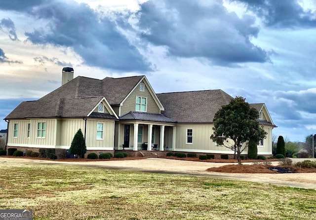 view of front of house with a chimney, metal roof, roof with shingles, a standing seam roof, and a front lawn