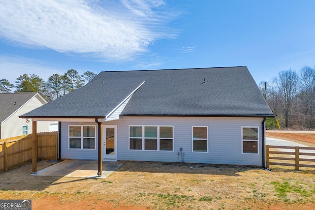 back of house with a patio, a yard, roof with shingles, and a fenced backyard