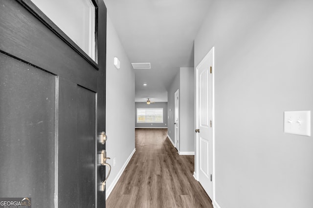 hall with visible vents, baseboards, and wood finished floors