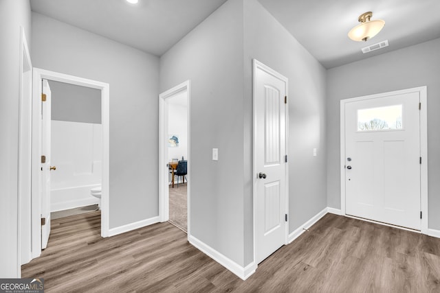 entrance foyer with baseboards, visible vents, and wood finished floors