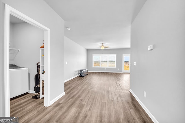 unfurnished living room with washer / dryer, baseboards, and wood finished floors