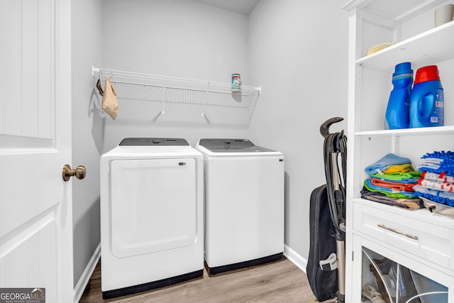 washroom with baseboards, laundry area, wood finished floors, and washer and dryer