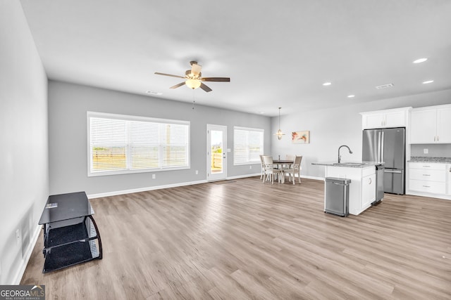 kitchen featuring light wood-style floors, freestanding refrigerator, white cabinetry, and a sink