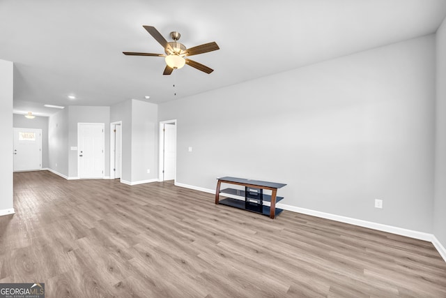 unfurnished living room featuring ceiling fan, wood finished floors, and baseboards