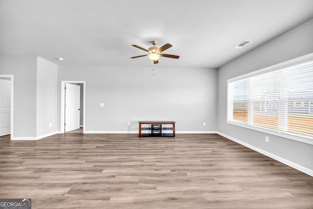 unfurnished living room with a ceiling fan, visible vents, baseboards, and wood finished floors