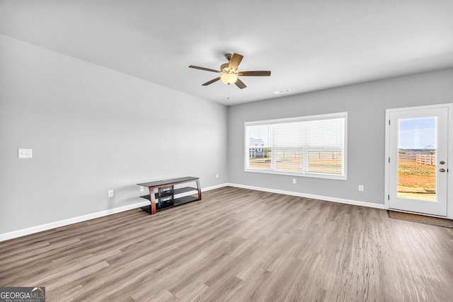 unfurnished room with a ceiling fan, visible vents, baseboards, and wood finished floors