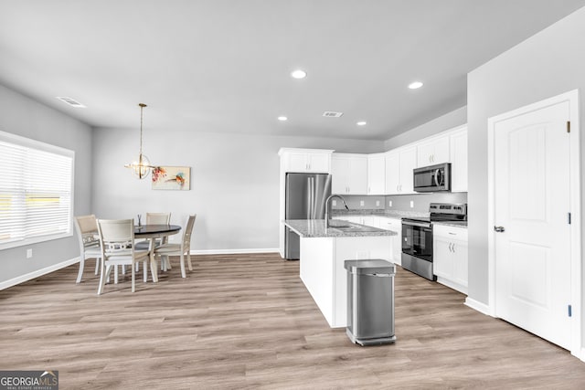 kitchen featuring appliances with stainless steel finishes, white cabinetry, light stone counters, and light wood finished floors