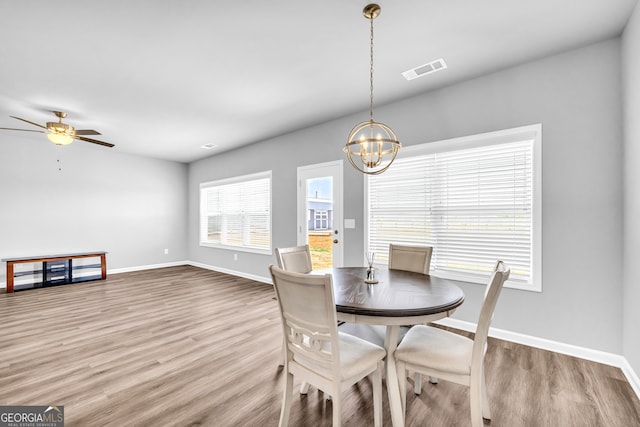 dining room with ceiling fan with notable chandelier, visible vents, baseboards, and wood finished floors