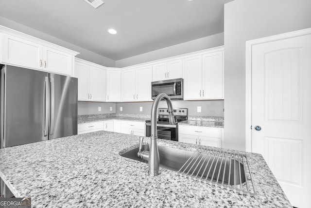 kitchen featuring stainless steel appliances, recessed lighting, light stone countertops, and white cabinets