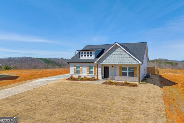 view of front of house with covered porch, a front lawn, central AC, and brick siding