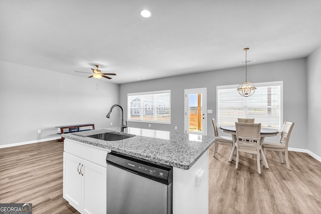 kitchen featuring white cabinets, light wood-type flooring, stainless steel dishwasher, pendant lighting, and a sink