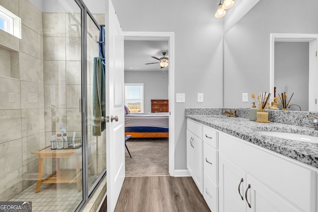 ensuite bathroom featuring connected bathroom, a shower stall, a sink, and wood finished floors