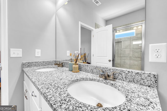 full bath with double vanity, tiled shower, and a sink