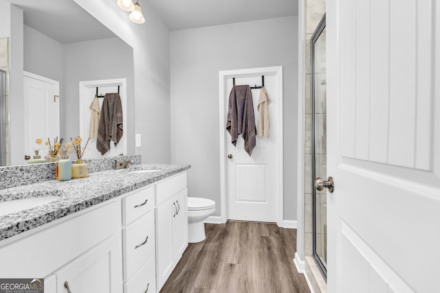 full bath with a stall shower, double vanity, a sink, and wood finished floors