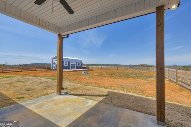 view of yard with a patio area, a rural view, ceiling fan, and a fenced backyard