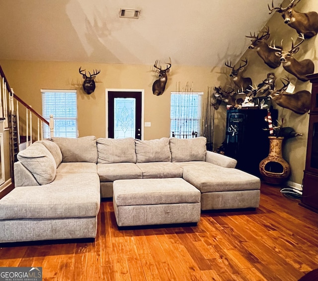 living room with stairs, lofted ceiling, visible vents, and wood finished floors