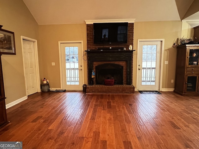 unfurnished living room with a wealth of natural light, a fireplace, vaulted ceiling, and wood finished floors