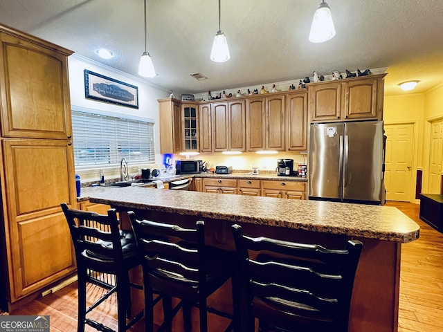 kitchen with light wood-style flooring, a sink, freestanding refrigerator, and crown molding