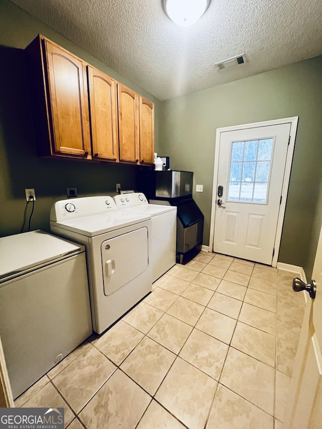 clothes washing area with light tile patterned floors, cabinet space, visible vents, a textured ceiling, and separate washer and dryer