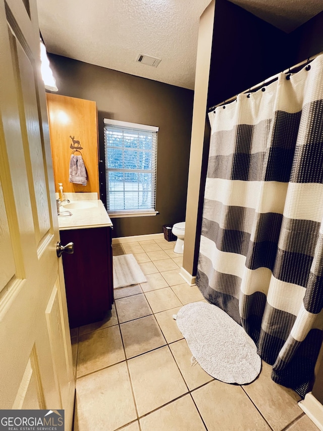 bathroom featuring toilet, a textured ceiling, visible vents, and tile patterned floors