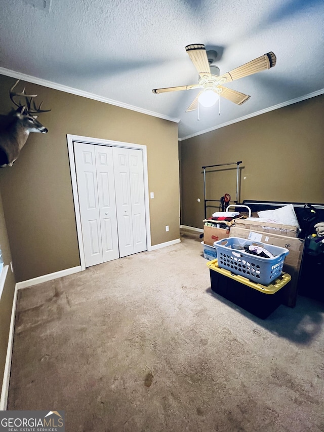 carpeted bedroom with baseboards, a ceiling fan, a textured ceiling, crown molding, and a closet