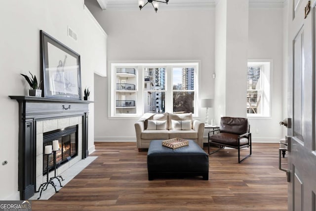 living area with ornamental molding, a fireplace, and wood finished floors