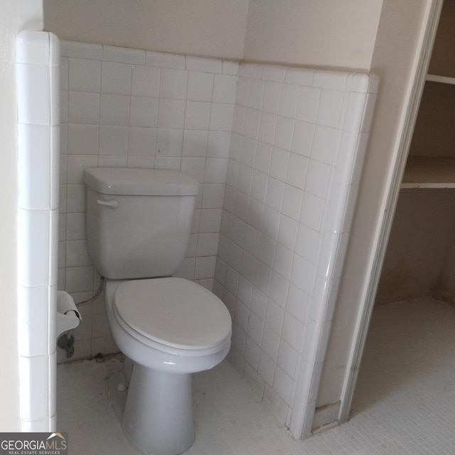 bathroom with toilet, tile patterned flooring, and tile walls