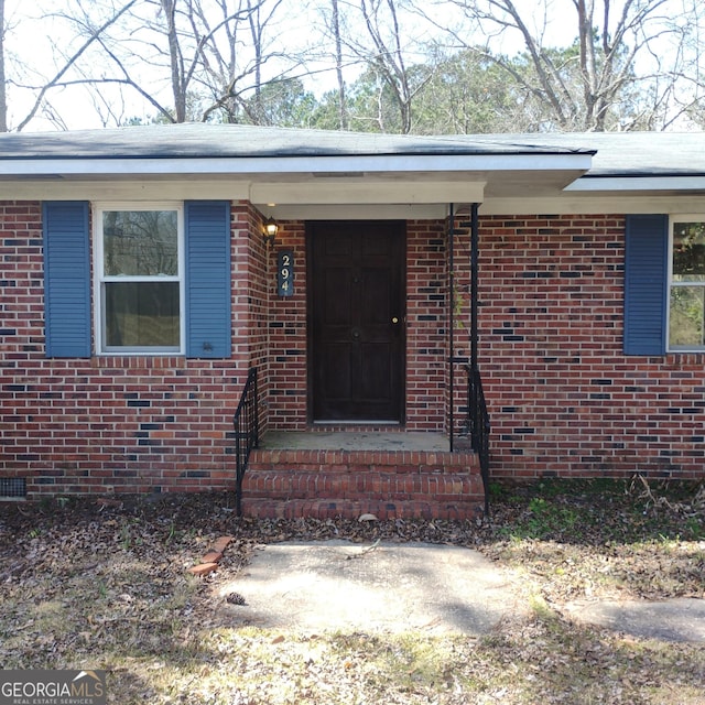 view of exterior entry with crawl space and brick siding