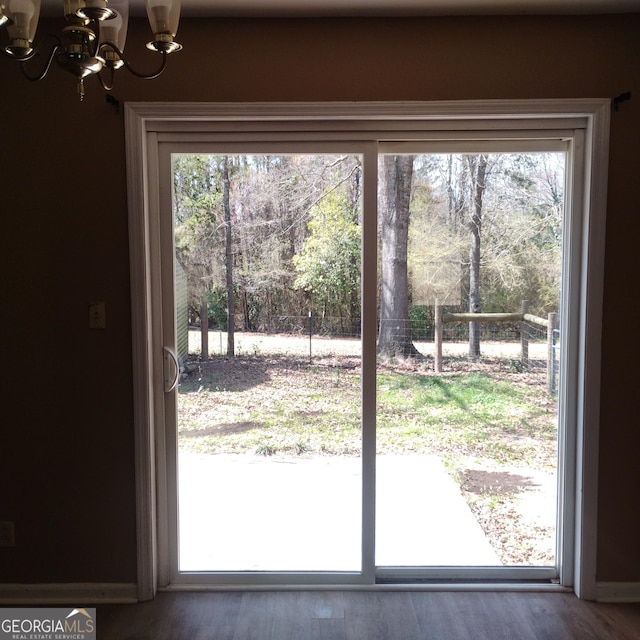 entryway with a wealth of natural light, wood finished floors, and an inviting chandelier