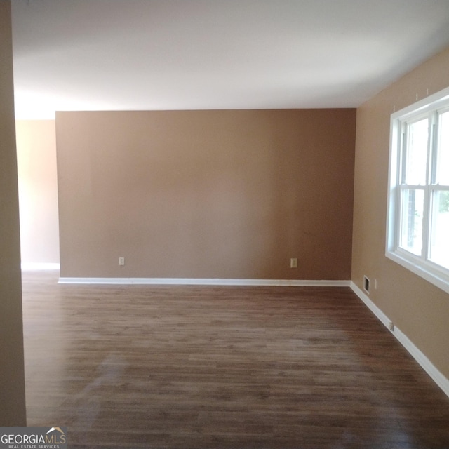 spare room featuring dark wood-style flooring and baseboards