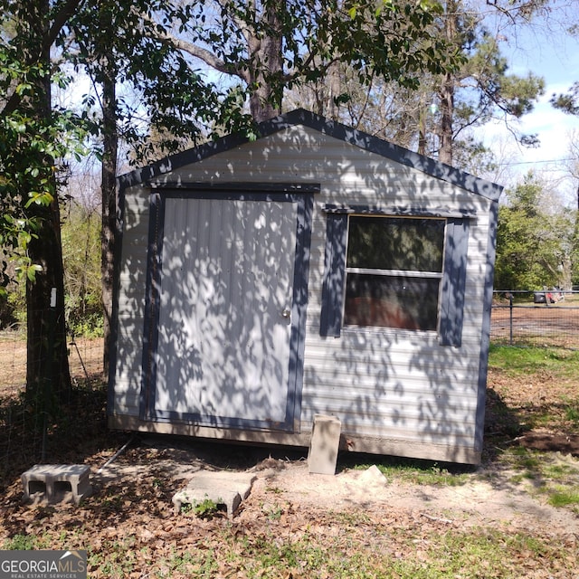 view of home's exterior featuring an outdoor structure, fence, and a shed