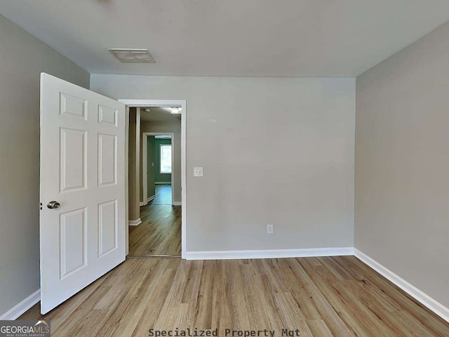 unfurnished room featuring light wood-style floors, visible vents, and baseboards