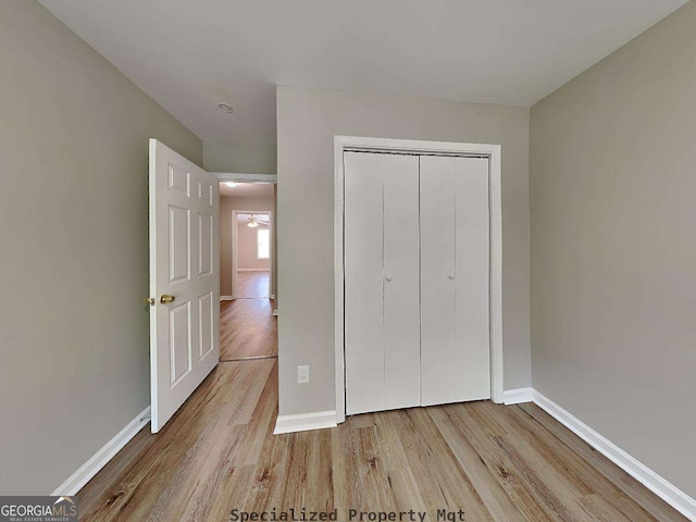 unfurnished bedroom featuring a closet, baseboards, and wood finished floors