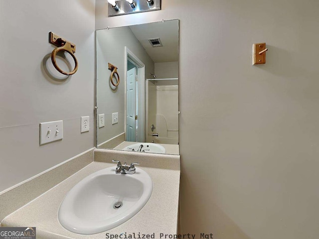 bathroom with visible vents, a shower, and vanity